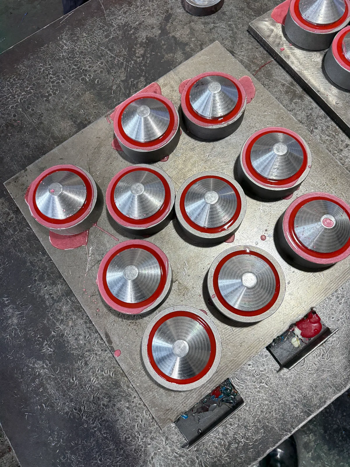 Red polyurethane feed wheels in circular moulds on a workshop bench during casting